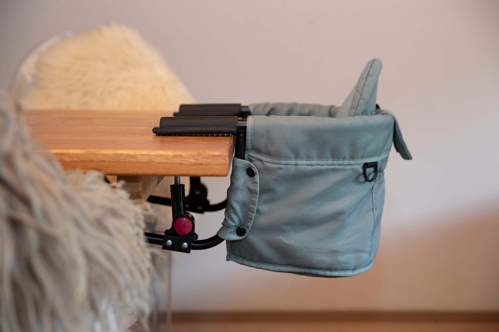 A chair-like seat that is attached to a table. The seat has soft padding and a practical pocket on the side.