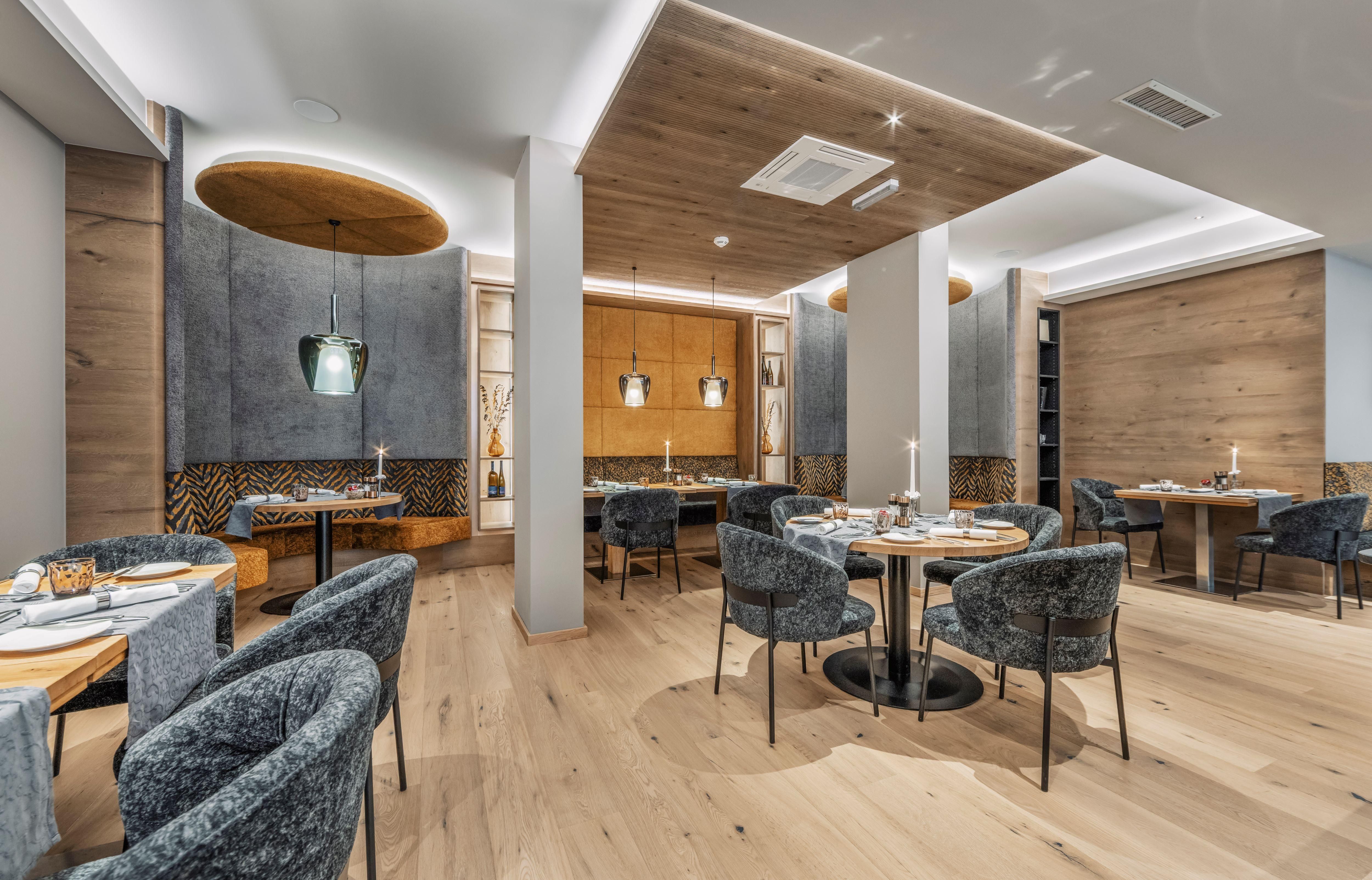 A modern restaurant with stylish round tables and comfortable chairs. The walls are painted in neutral tones, complemented by appealing lighting elements.