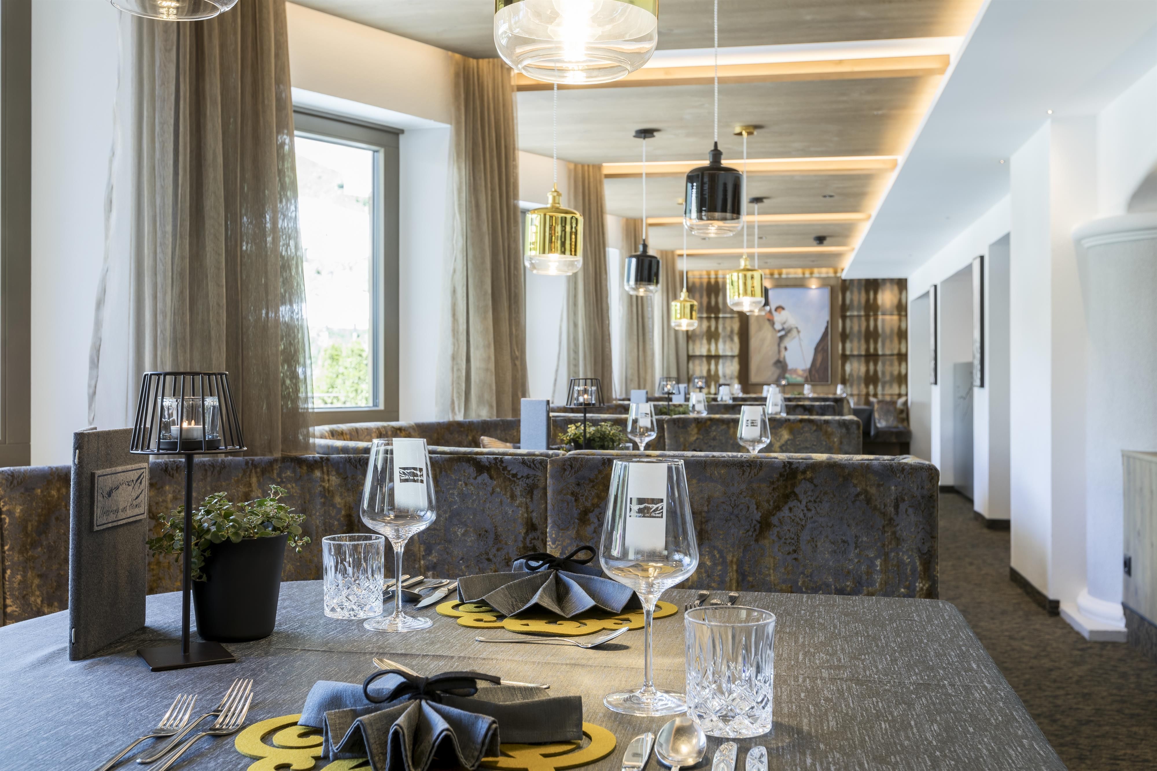 An elegant restaurant with modern furniture and stylishly set tables. Large windows provide plenty of daylight and create an inviting atmosphere.