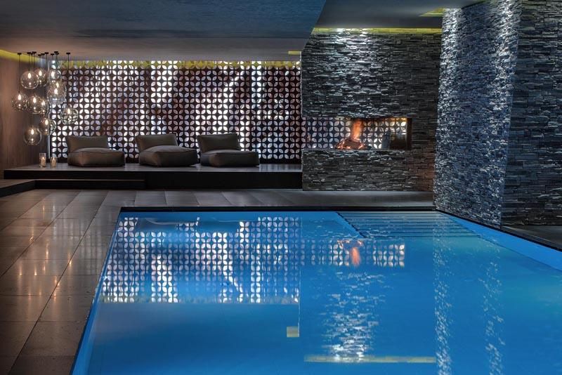 A stylish spa with a clear pool and relaxing seating. Soft lighting and modern elements create a tranquil atmosphere.