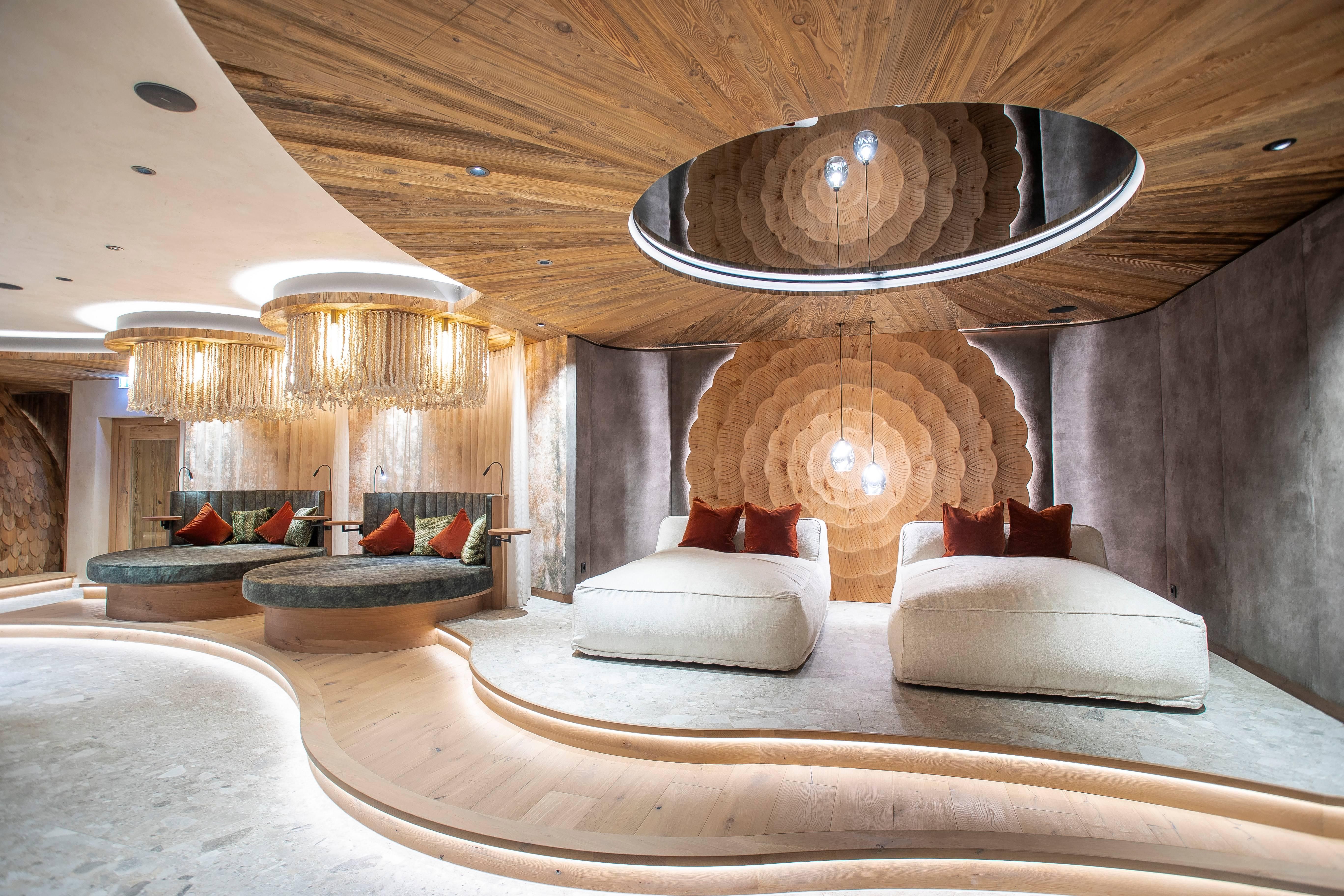 An elegant, modern space with wooden paneling and comfortable lounge furniture. Soft lighting and an artistic, round ceiling object create a relaxing atmosphere.