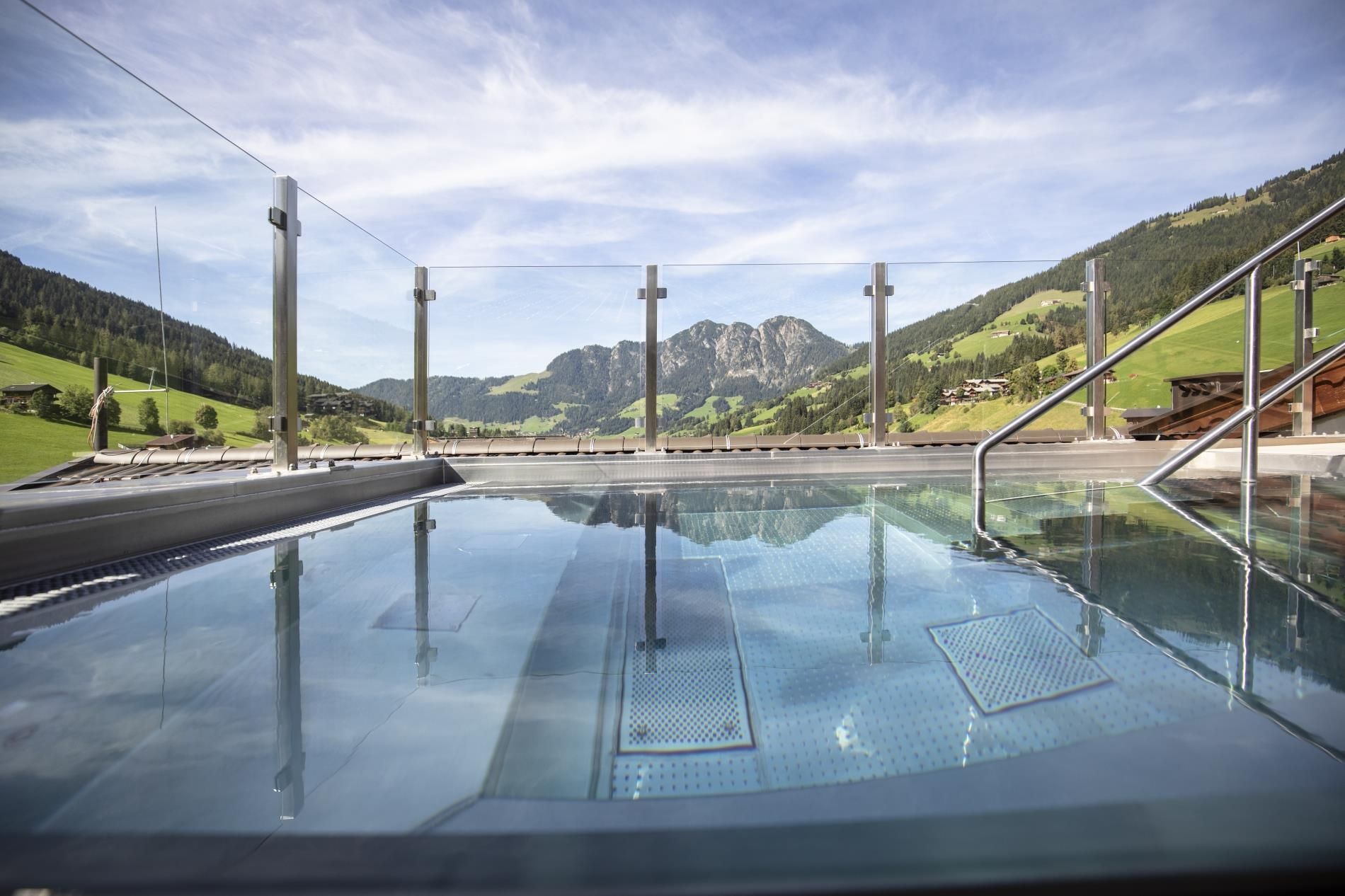 A swimming pool overlooking green hills and mountains. The sky is clear and the atmosphere is calm and relaxing.