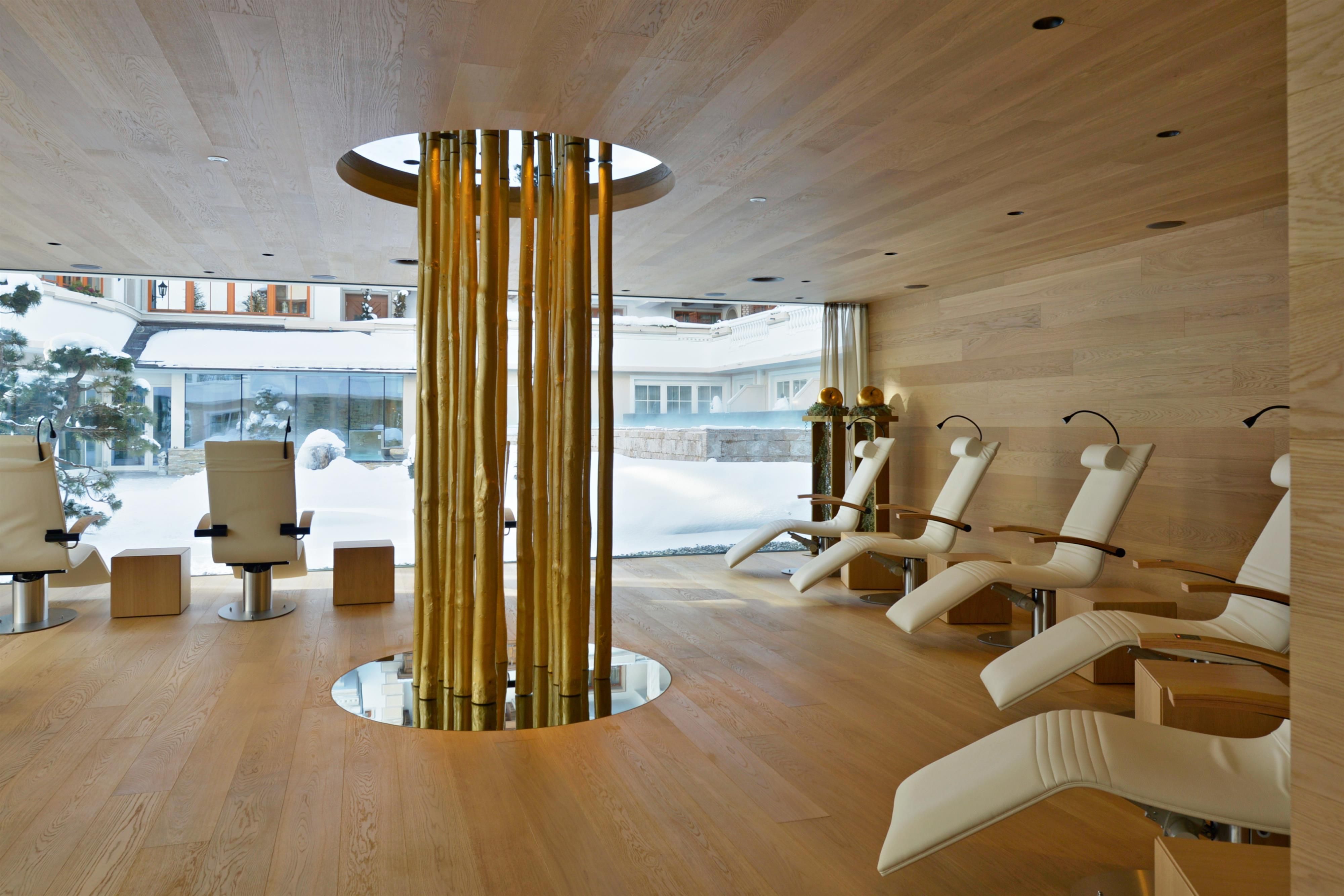 A modern wellness area with wooden decor and comfortable loungers. Large windows provide a view of the snow-covered landscape outside.