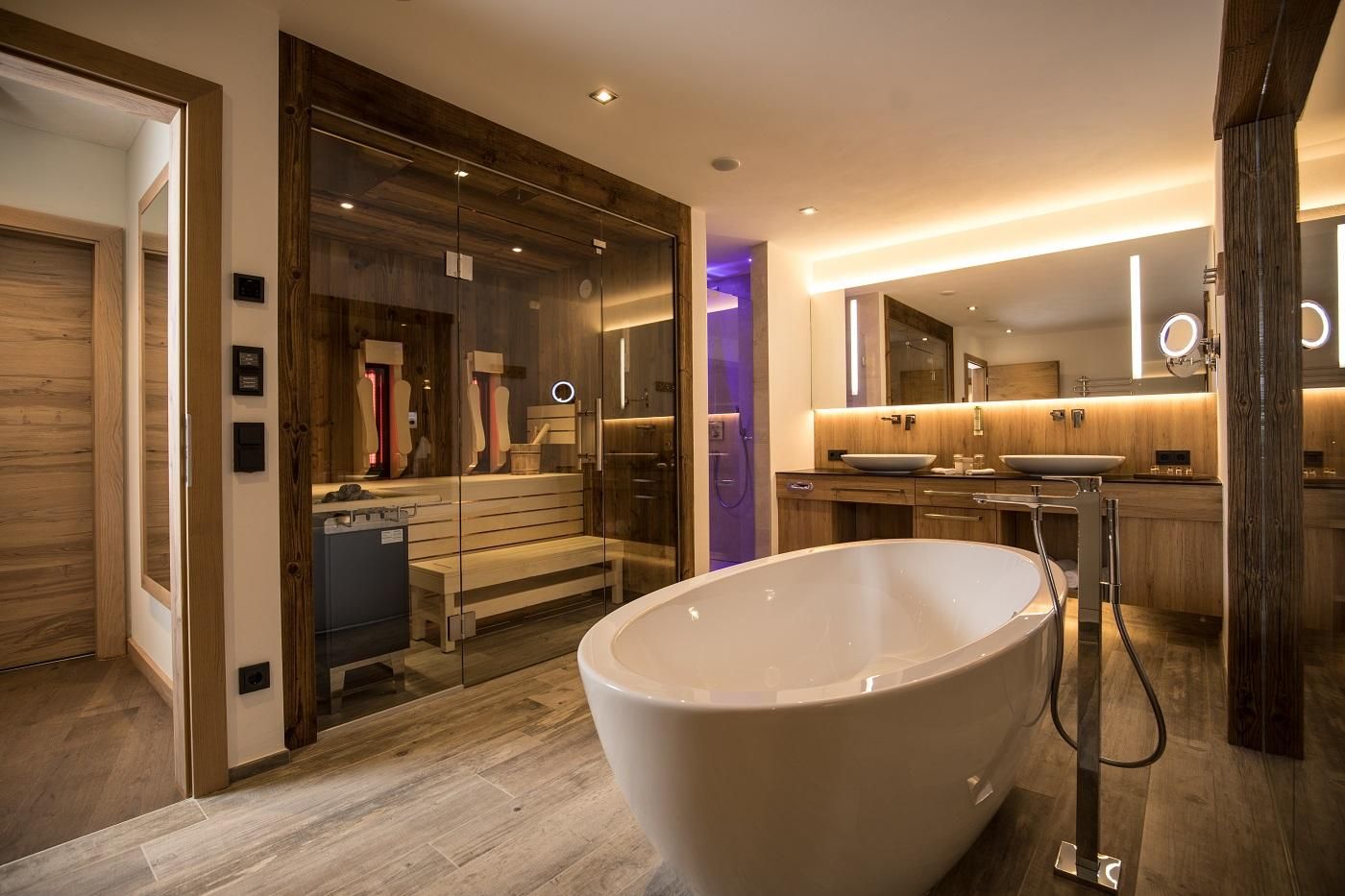 A modern bathroom with a freestanding bathtub and a sauna. The walls are made of wood and there is soft lighting.