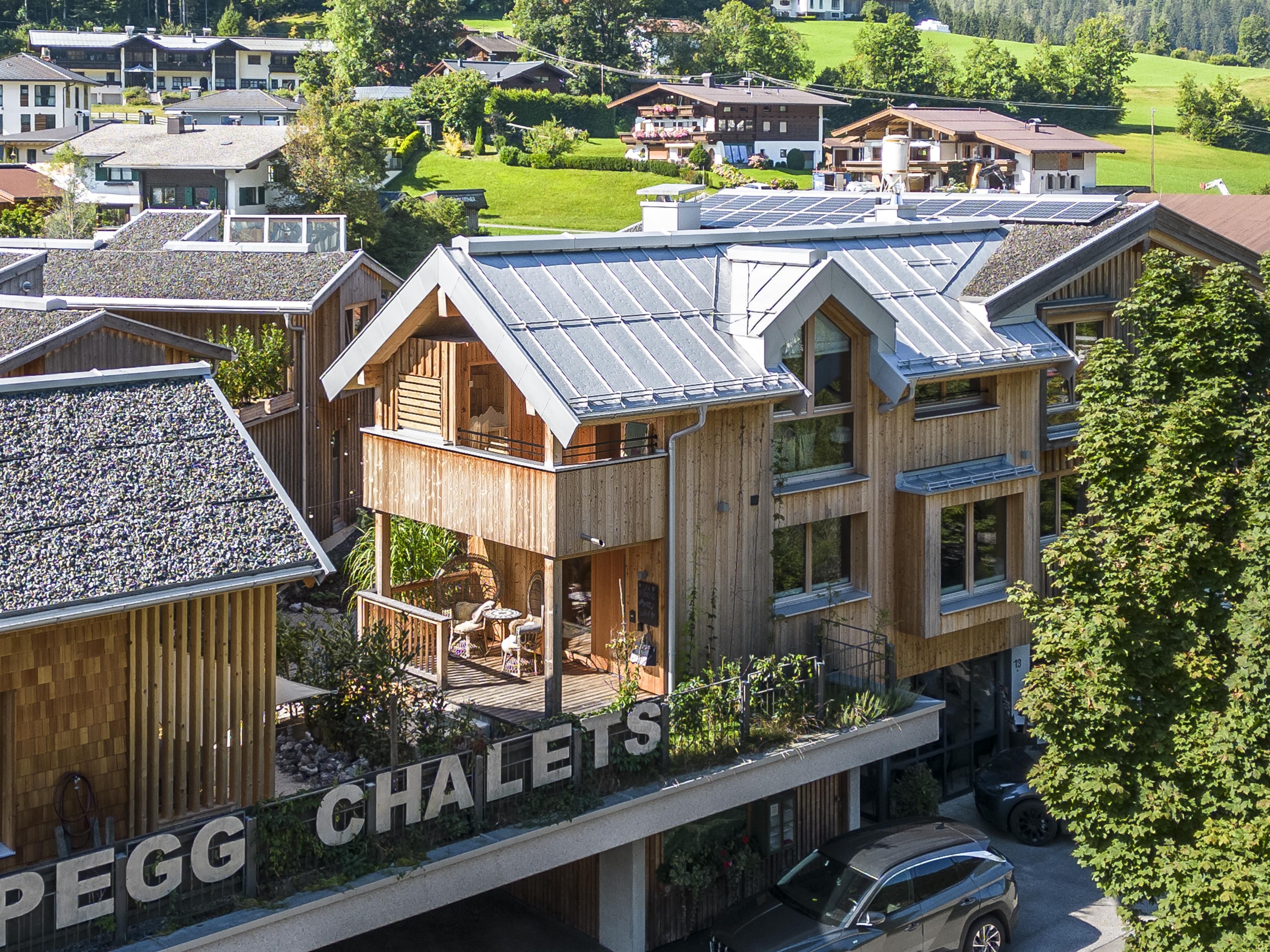 A modern chalet complex surrounded by green landscape. The buildings have wooden facades and provide a view of the idyllic surroundings.