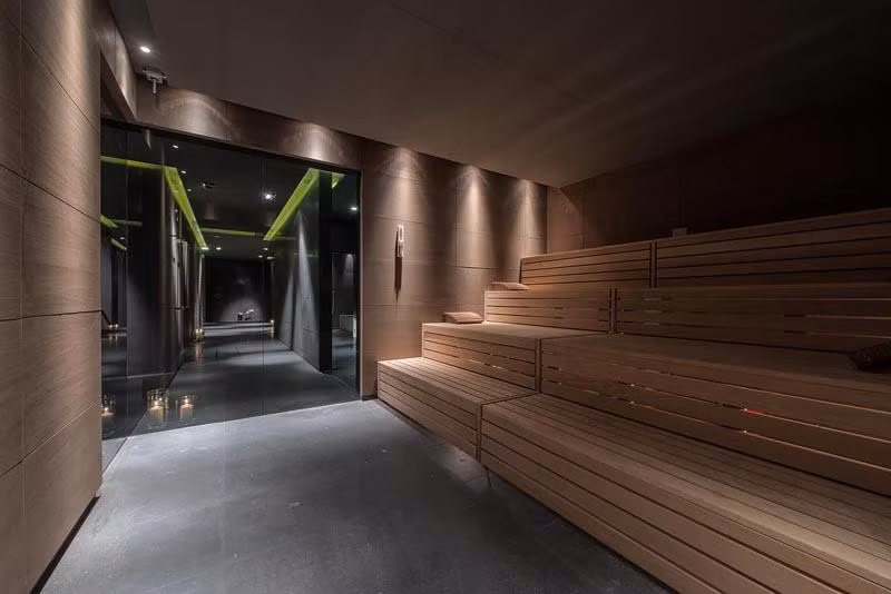 A modern sauna area with wooden benches and subdued lighting. The room radiates a relaxing atmosphere.