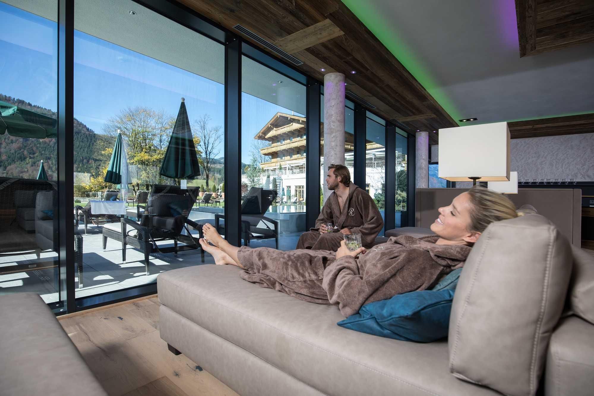 A relaxing wellness area with large windows overlooking the terrace. Two people in bathrobes enjoy the peaceful atmosphere.