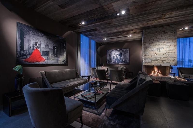 An elegant living space with modern furniture and a fireplace. Large windows let in soft light and beautiful artworks adorn the walls.