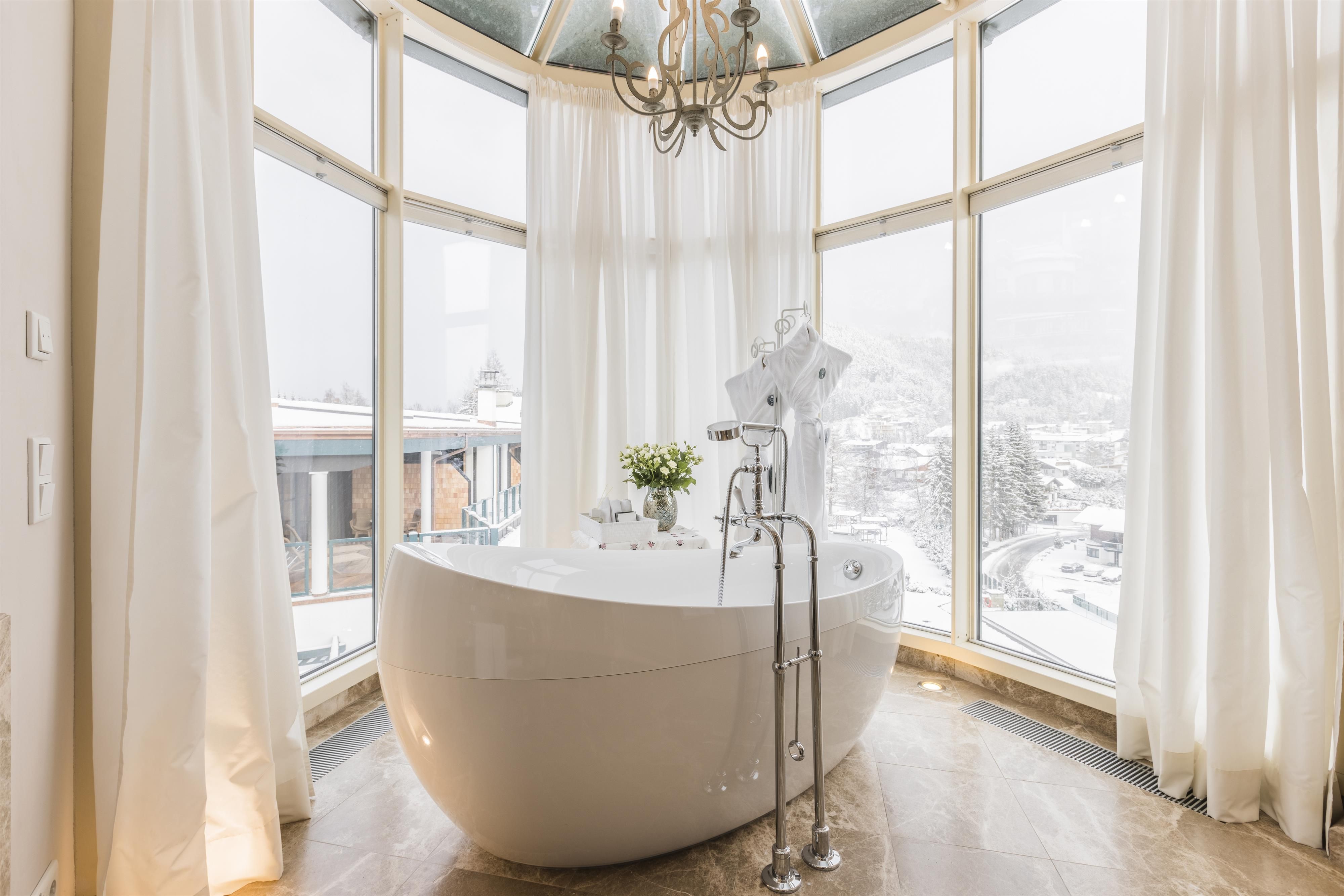 An elegant bathroom with a freestanding bathtub and large windows. The view of the snow-covered landscape creates a relaxing atmosphere.