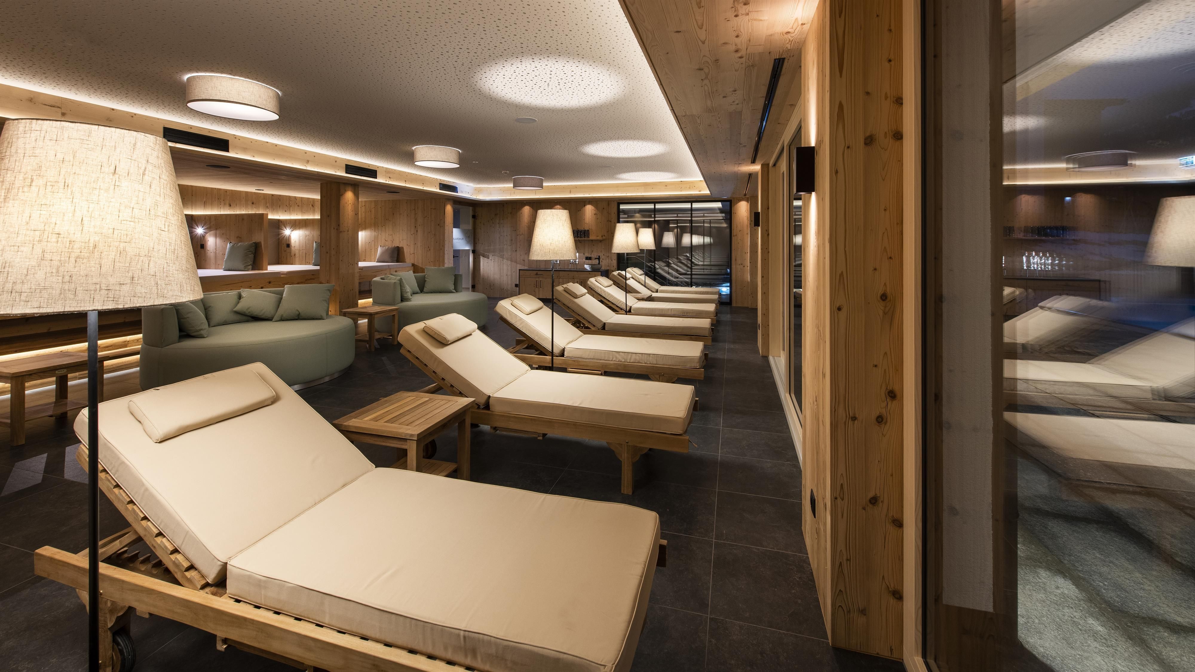 An elegant relaxation area with wooden loungers and soft lighting. The atmosphere is calm and inviting.