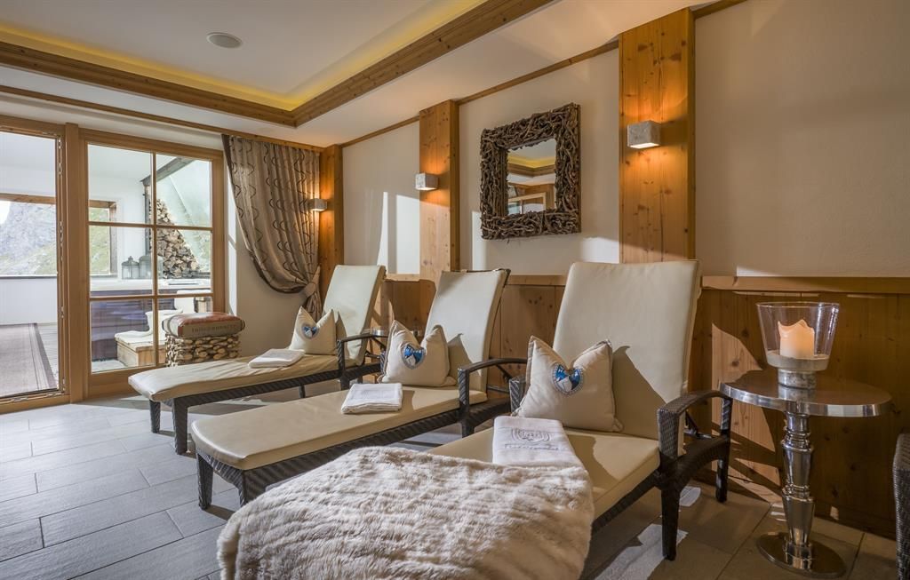 A relaxing wellness area with loungers and a cozy atmosphere. Large windows offer a view of nature.