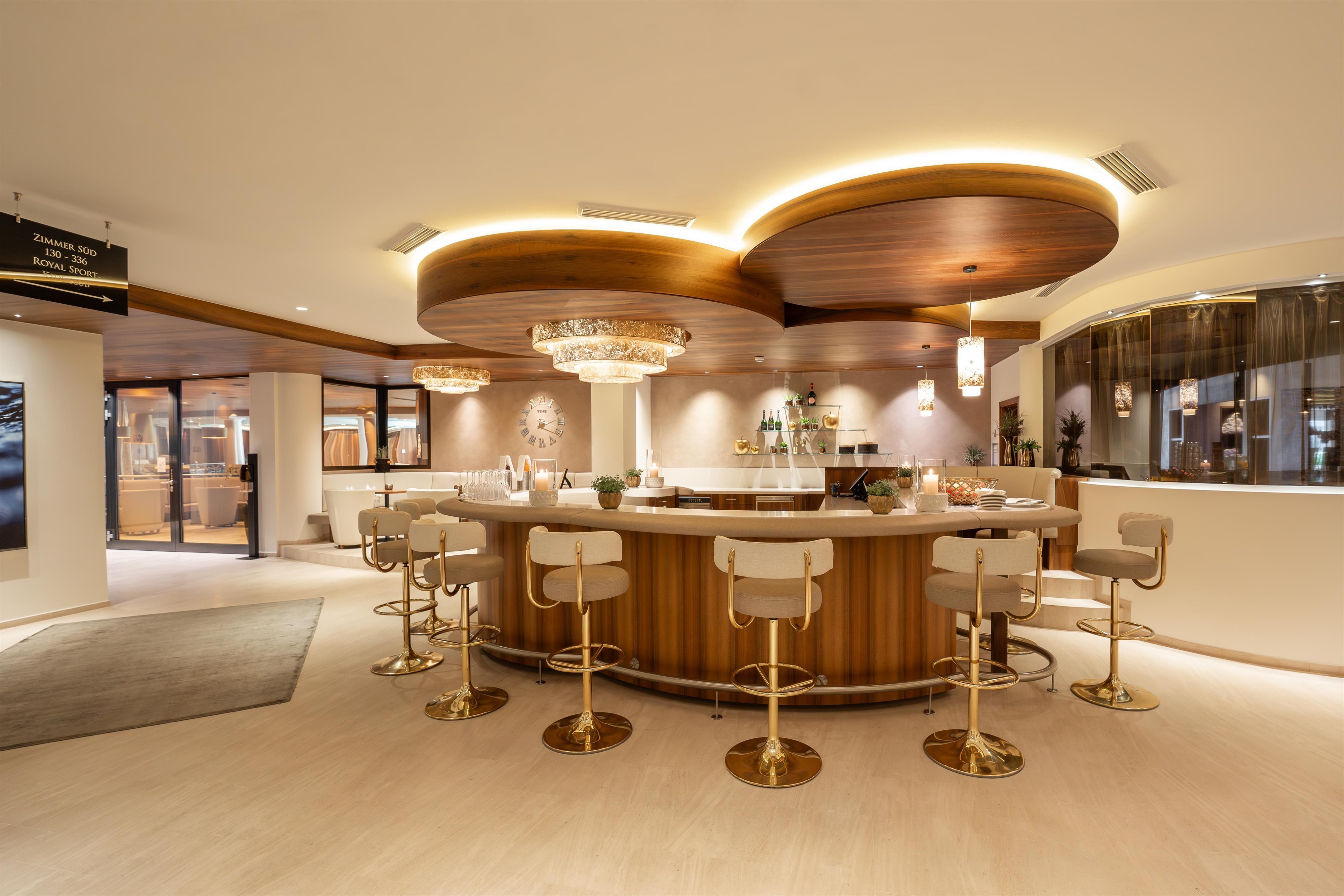An elegant bar with a round, well-lit counter and stylish bar stools. The decor is modern and inviting.