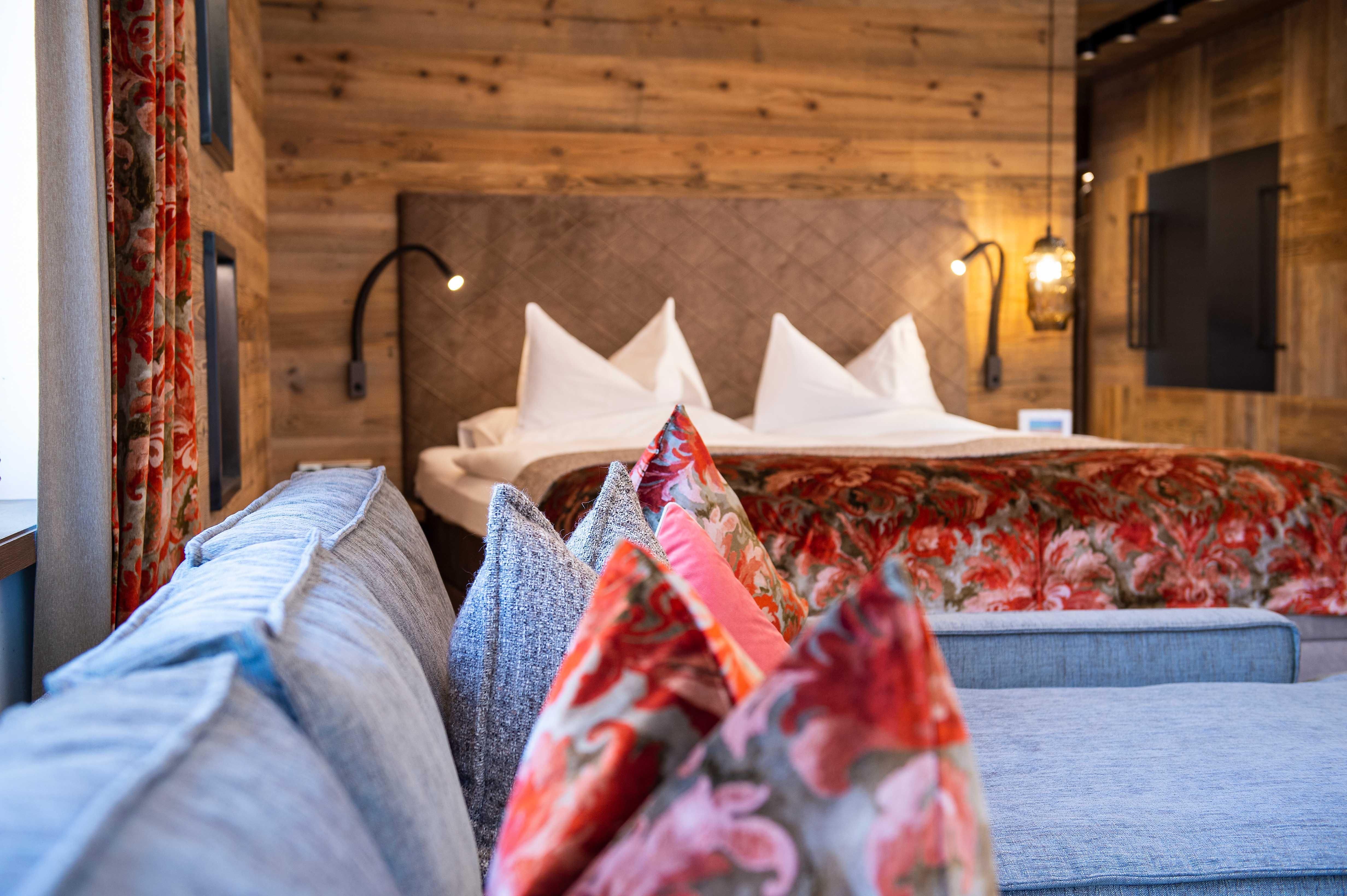 A cozy room with a large bed and elegant pillows. The wooden walls and warm colors create an inviting atmosphere.