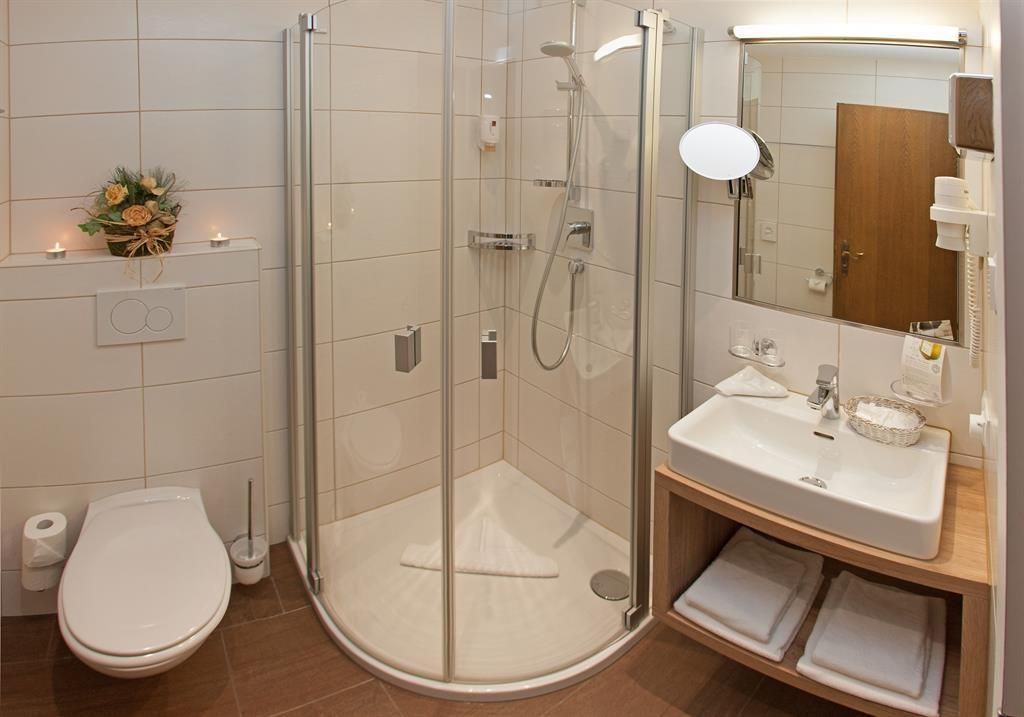 A modern bathroom with a shower cabin and a sink. There are bright tiles and a clean, inviting atmosphere.