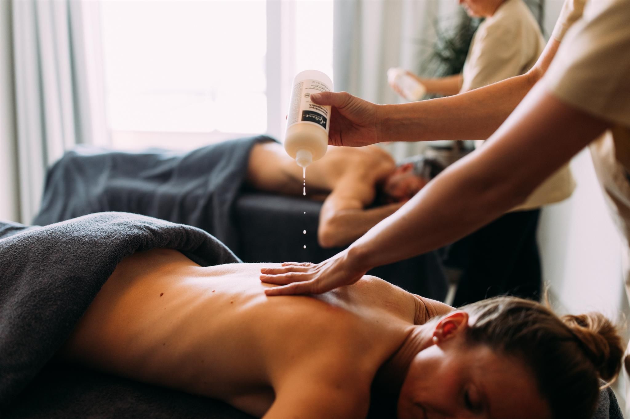 A relaxing massage in a wellness area. Two people are treated with oil by therapists.