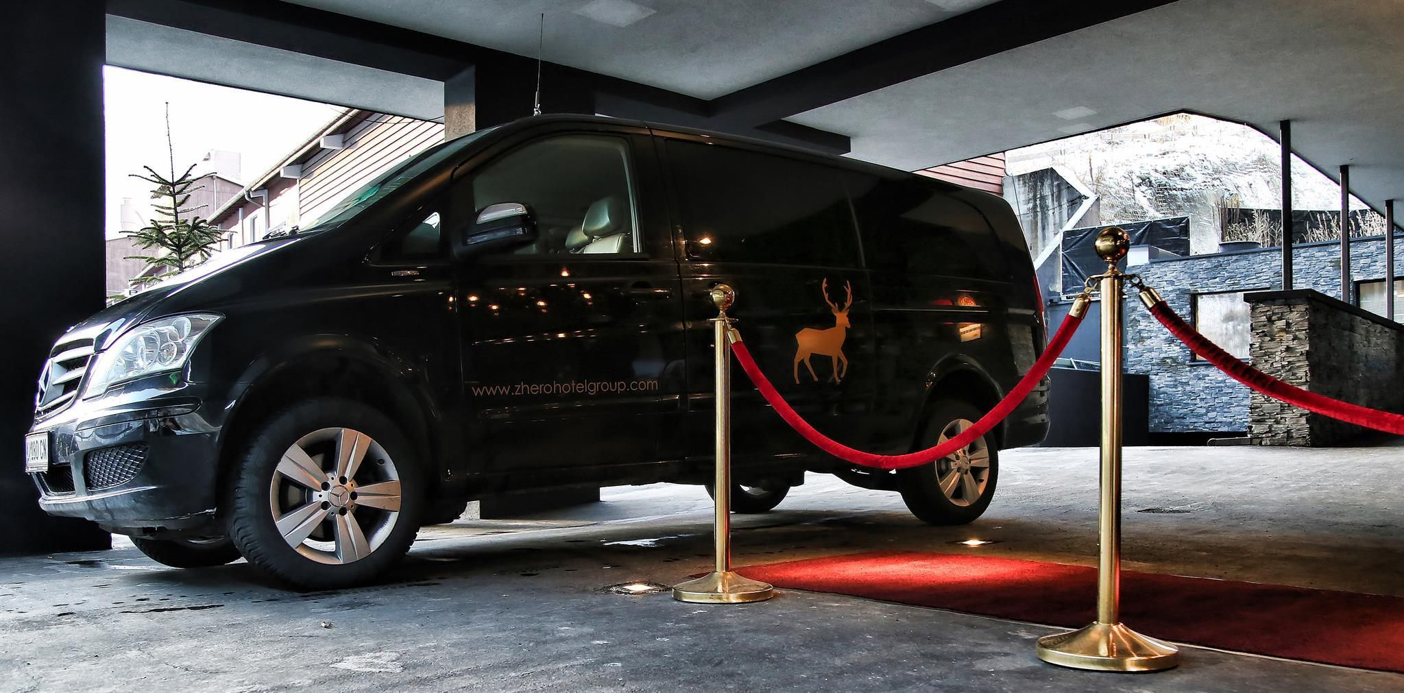A black van is parked in an elegant entrance area. Red barrier tapes and a stylish environment create a sophisticated atmosphere.