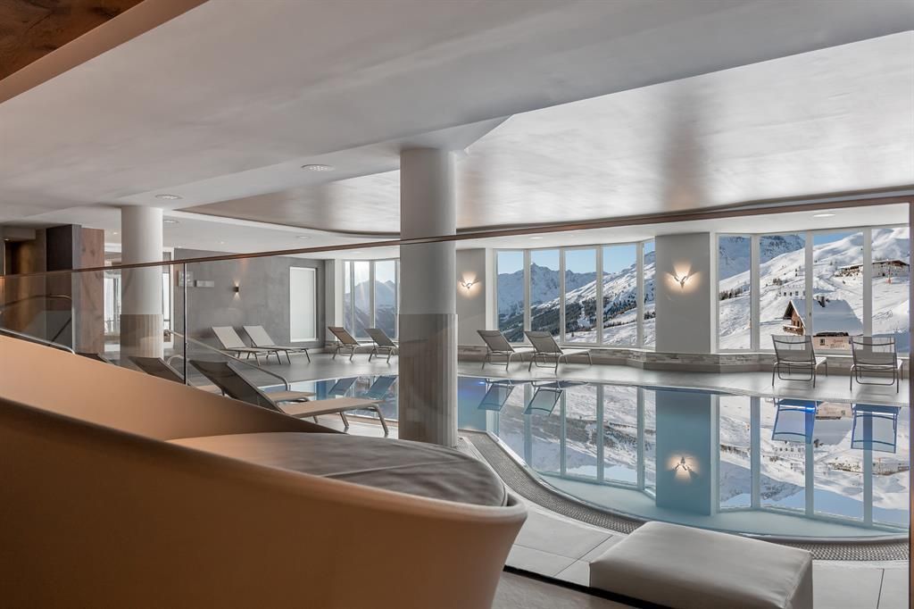 An elegant wellness area with an indoor pool and views of the snow-covered mountains. Large windows let in plenty of daylight and create a relaxing atmosphere.