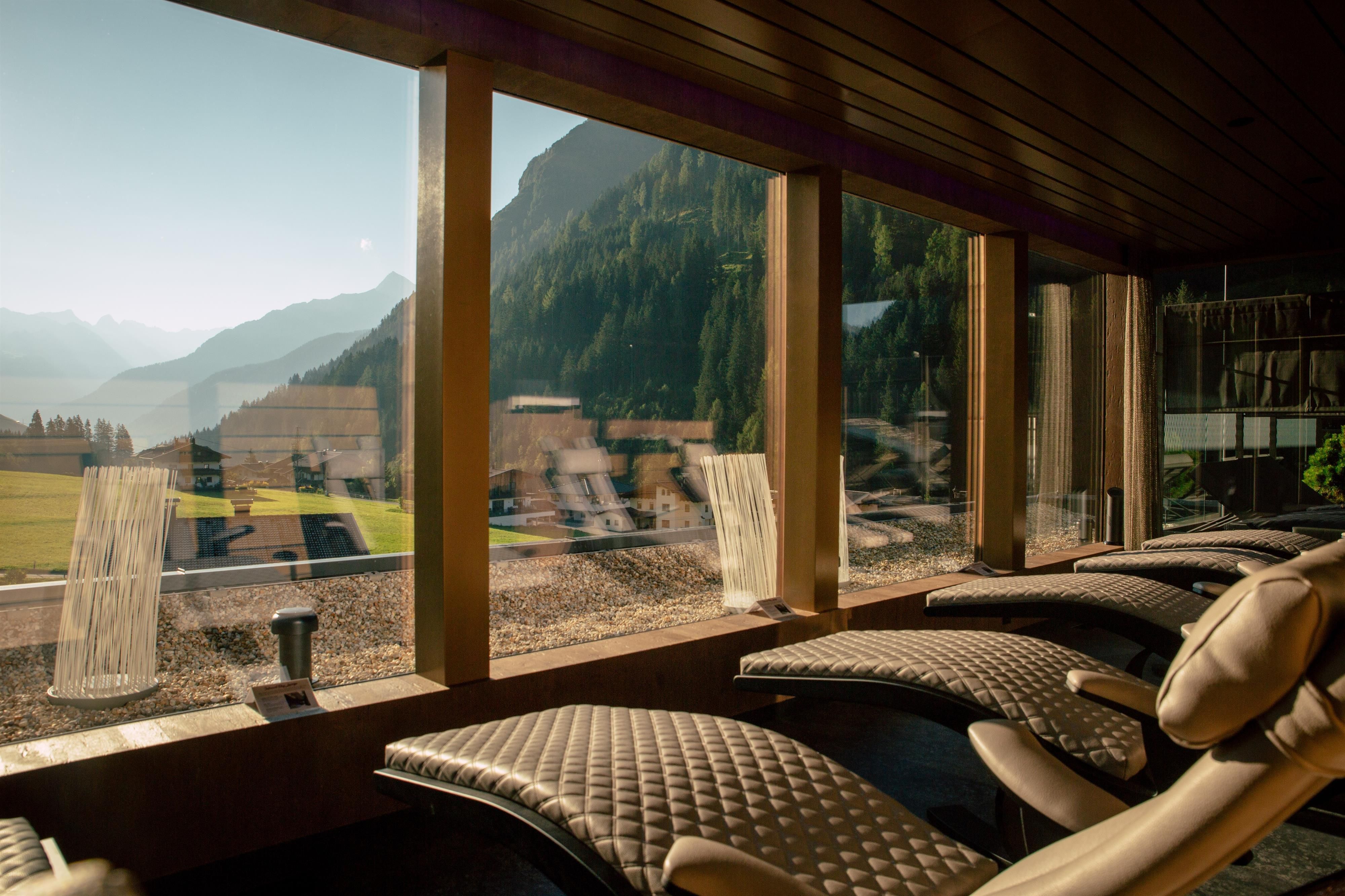 A relaxing wellness area with comfortable loungers and a view of the mountains. The large window lets in plenty of natural light and offers a beautiful view.