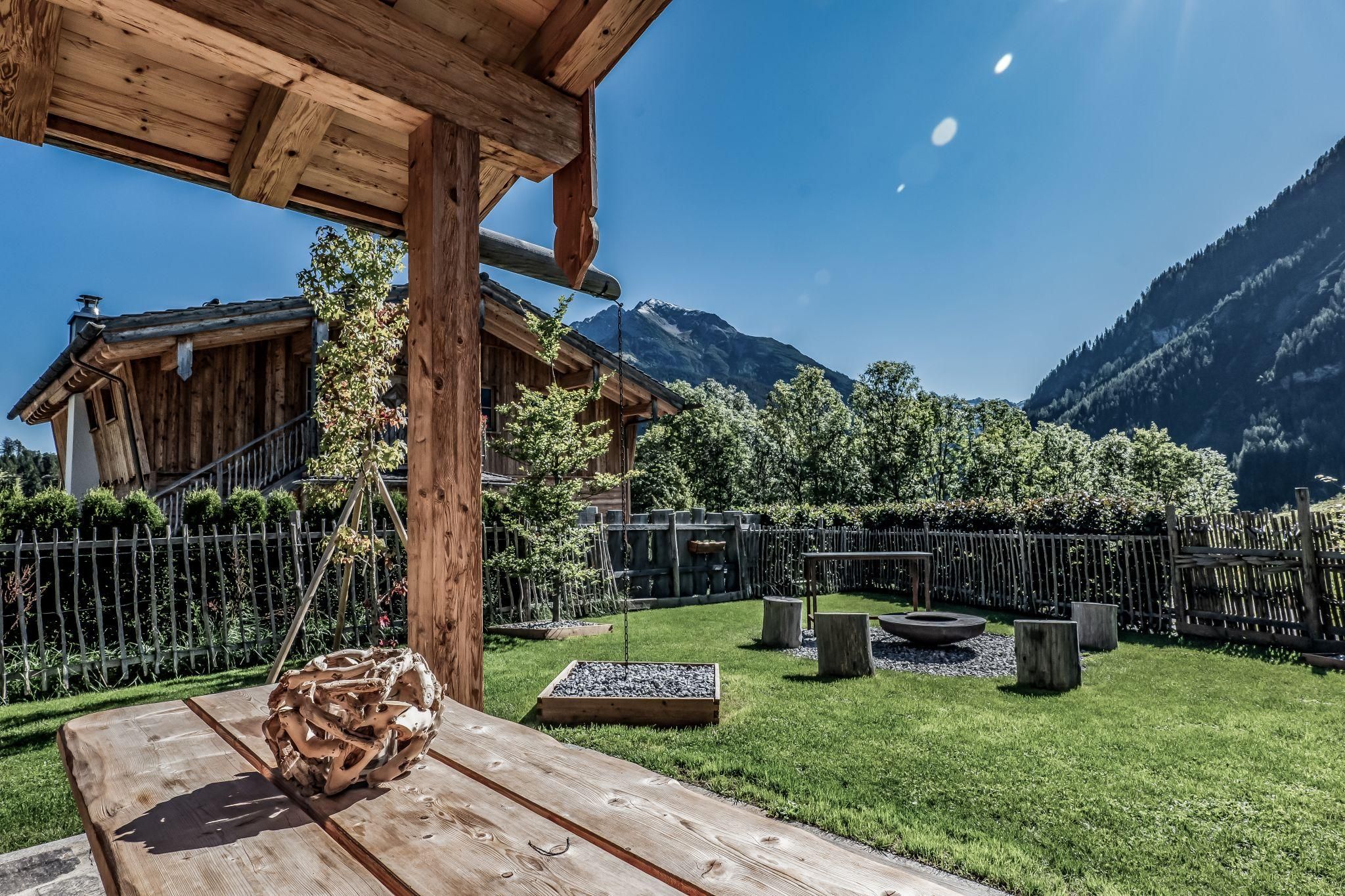 A beautiful garden with a wooden bench and a view of the mountains. The surroundings are green and invite you to relax.