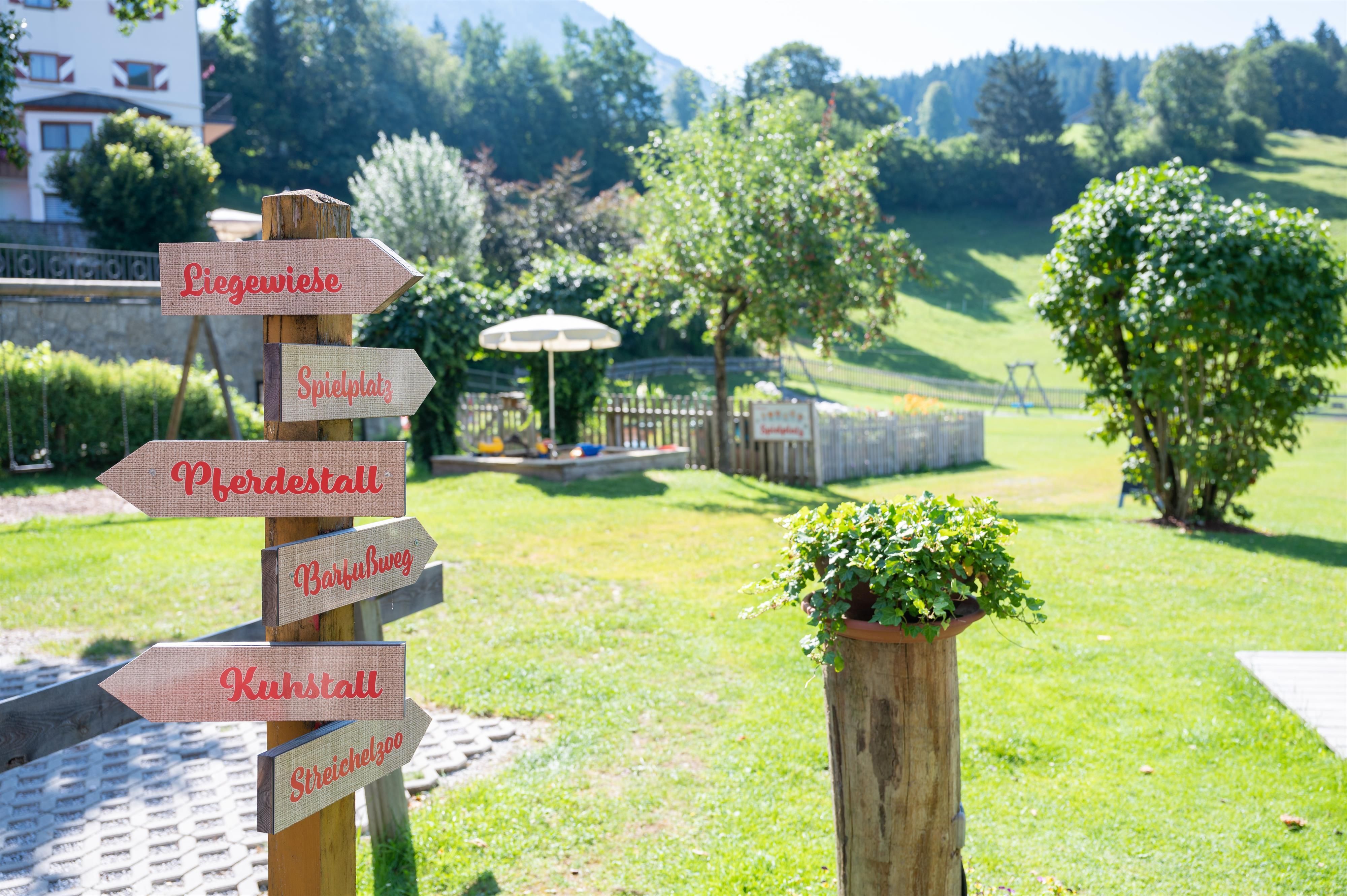 A beautiful garden with directional signs. In the background, trees and a green meadow can be seen.