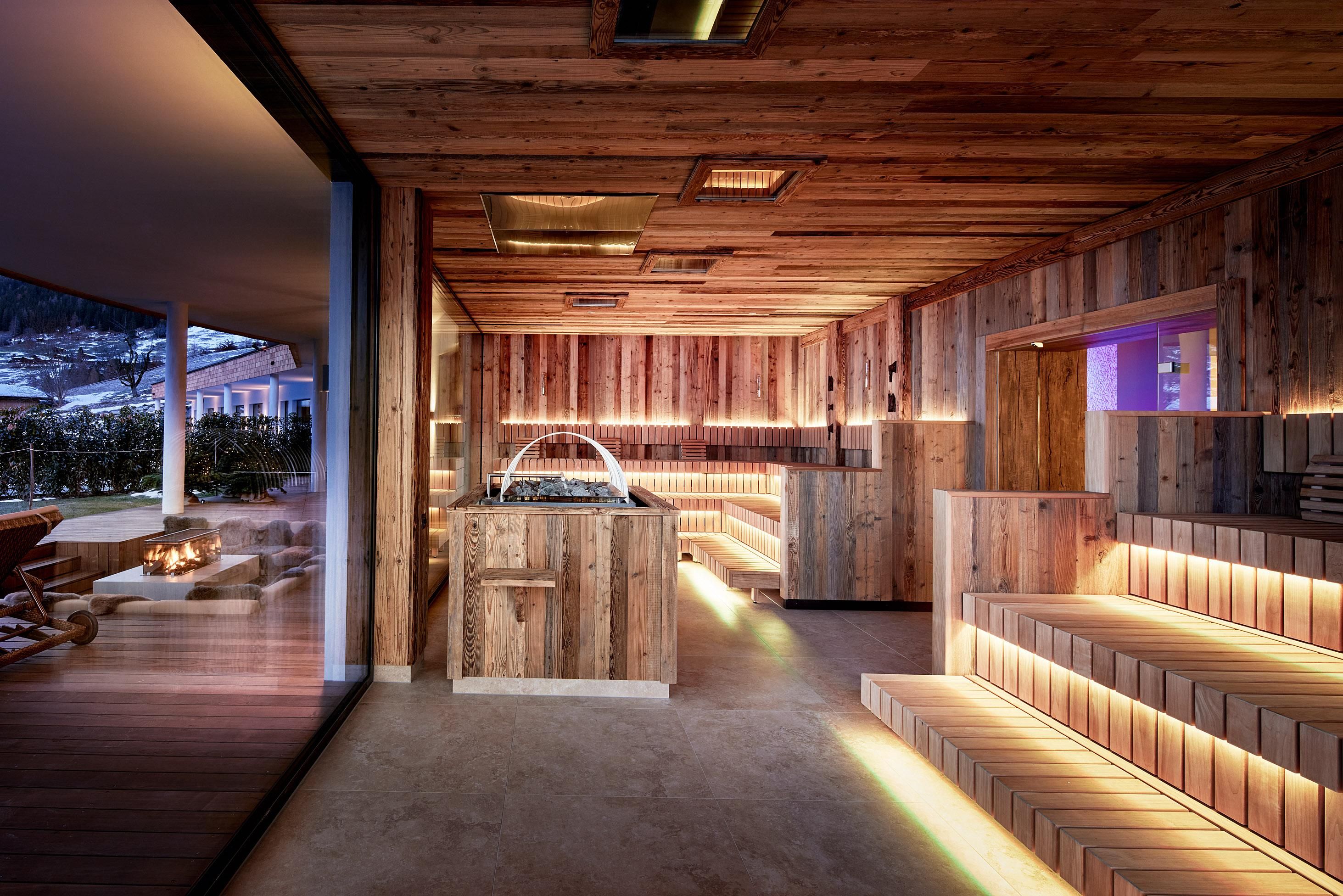 A modern wellness area made of wood with a cozy atmosphere. The room is warmly lit and offers various relaxation options.