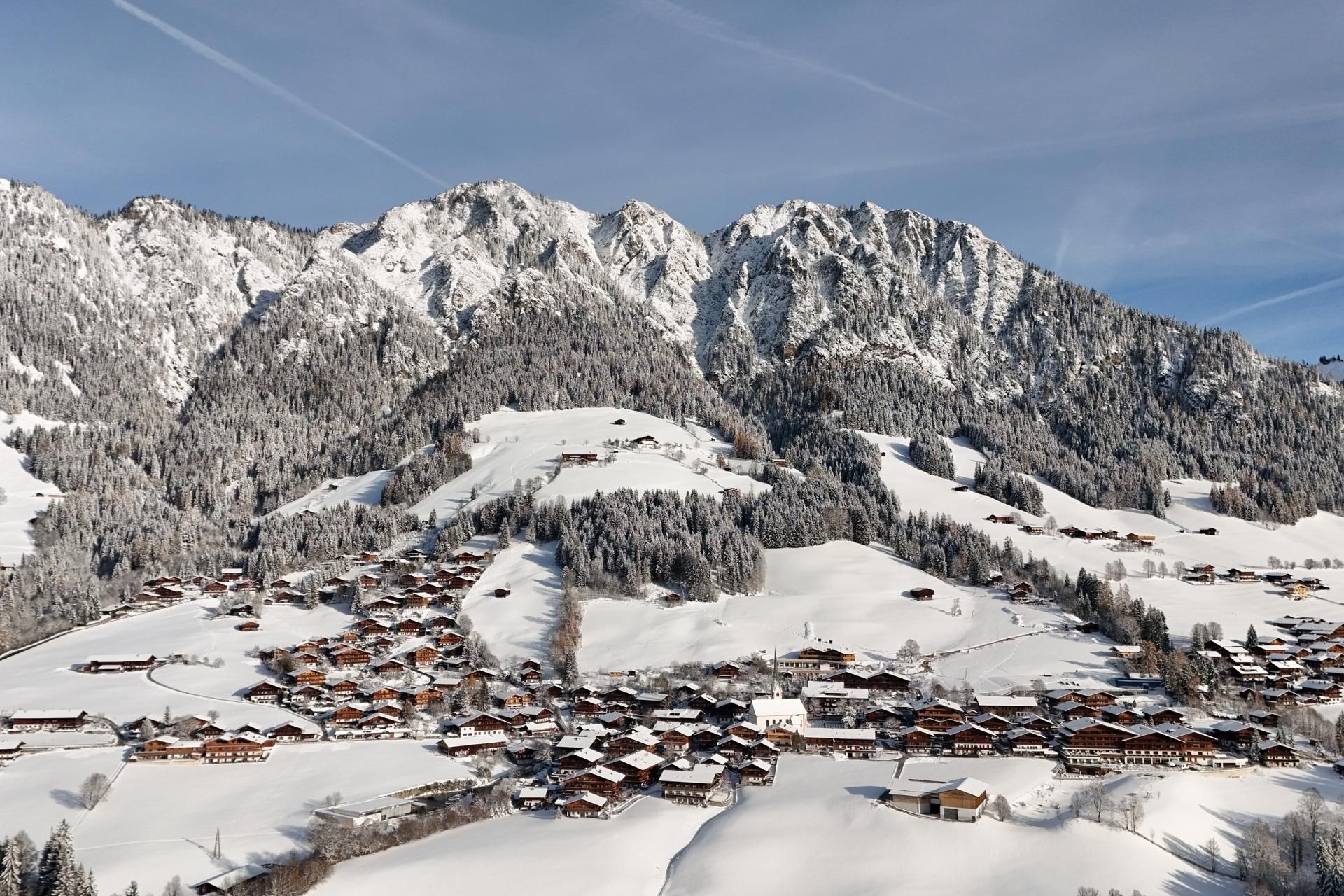 A picturesque winter landscape with snow-covered mountains and a small village. The snow-covered hills invite outdoor activities.